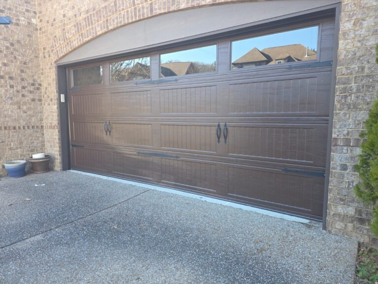 Dark walnut garage door with arched windows on a brick home