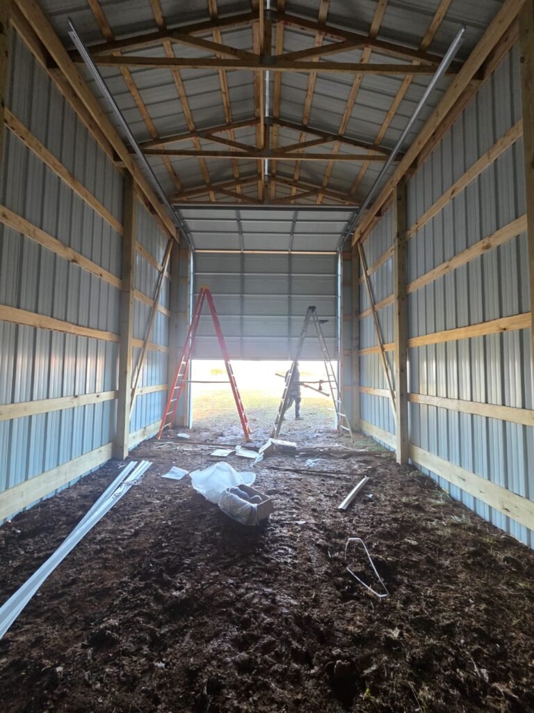 Garage door installation underway inside a pole barn