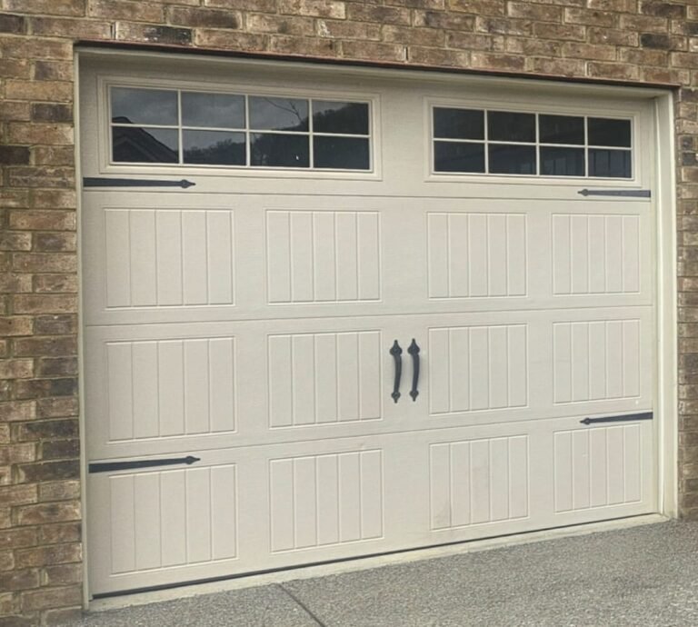 Cream carriage-style garage door with windows on a brick home