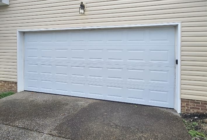 White raised-panel garage door on a tan-sided home
