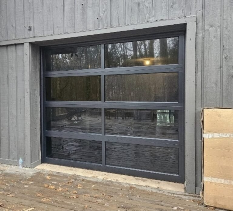 Modern black aluminum and glass garage door on a grey timber building