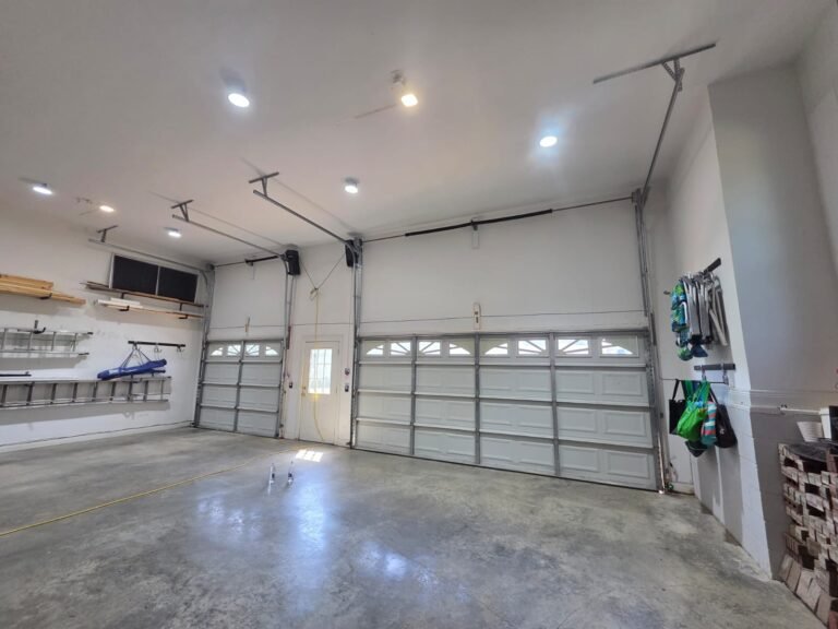 Two new white garage doors installed inside a clean garage