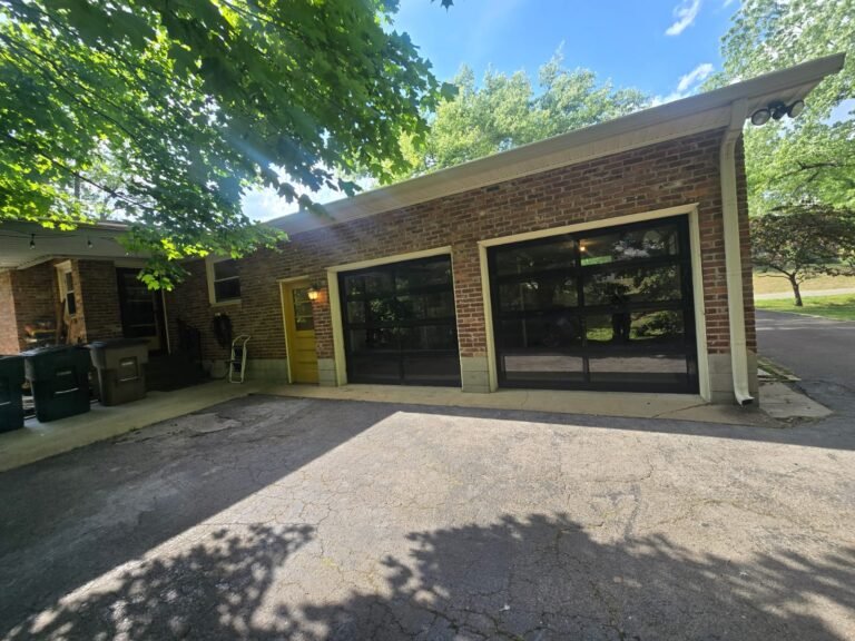 Black aluminum and glass garage doors on a red brick home