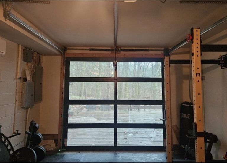 Black aluminum and glass garage door opening onto a deck