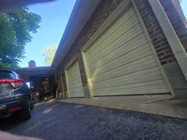 Aging cream roll-up garage doors on a brick garage, before replacement